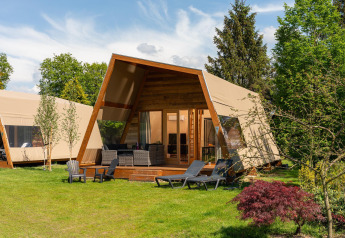 Tente lodge safari XL avec sanitaires au Holiday Resort 't Schuttenbelt, Pays-Bas, entouré de verdure.