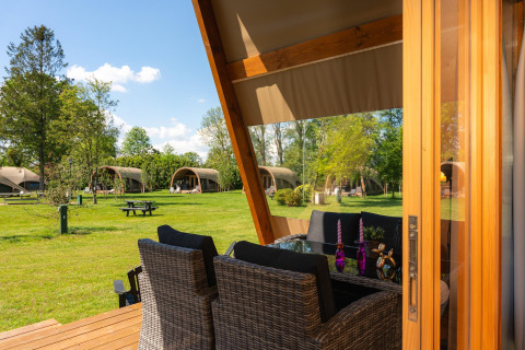 Uitzicht vanaf een terras met eettafel op safaritenten bij Vakantiepark 't Schuttenbelt in Nederland.