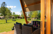 View from a terrace with dining area looking out to safari tents at Holiday Resort 't Schuttenbelt, Netherlands.