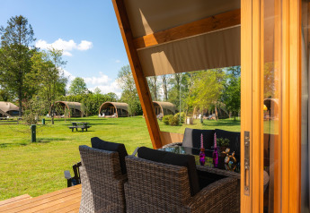 View from a terrace with dining area looking out to safari tents at Holiday Resort 't Schuttenbelt, Netherlands.