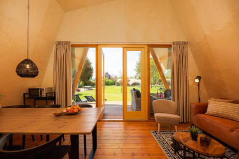 Binnenzicht van een XL safaritentlodge met hedendaags meubilair en zicht op een groene buitenomgeving.