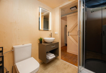 Salle de bain moderne dans une tente safari avec douche, toilettes, lavabo et miroir au 't Schuttenbelt.