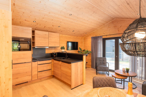 Modern lodge kitchen with wood interior, cozy sitting area, and large windows opening to a terrace view.