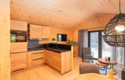 Cocina de lodge moderna con interior de madera, área de estar y ventanales hacia la terraza y el jardín.