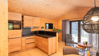 Moderne lodgekøkken med trægulve og -vægge, siddeområde og store vinduer med udsigt til terrassen.