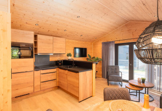 Cocina de lodge moderna con interior de madera, área de estar y ventanales hacia la terraza y el jardín.