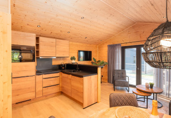 Moderne lodgekøkken med trægulve og -vægge, siddeområde og store vinduer med udsigt til terrassen.
