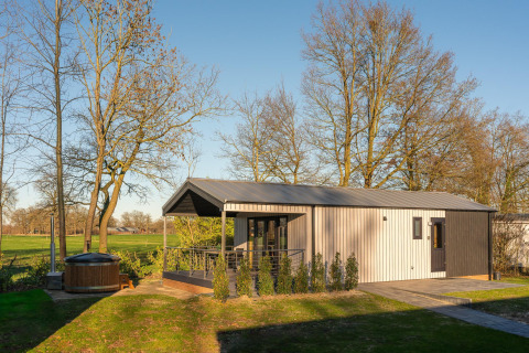 Terrassen-Lodge mit Sauna und Hot Tub im Holiday Resort 't Schuttenbelt, umgeben von Bäumen in den Niederlanden.