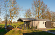 Terrassen-Lodge mit Sauna und Hot Tub im Holiday Resort 't Schuttenbelt, umgeben von Bäumen in den Niederlanden.