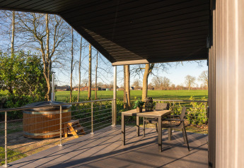 Überdachte Terrasse mit Tisch, Stühlen und Hot Tub im Holiday Resort 't Schuttenbelt in den Niederlanden.