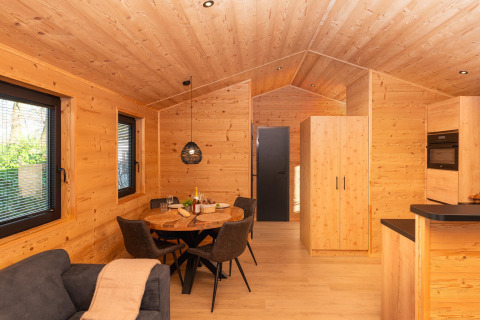 Træinteriør i Terrace Lodge med spisebord, sofa og moderne faciliteter på Holiday Resort 't Schuttenbelt.