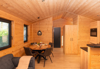 Interior de madera de la Terrace Lodge con mesa de comedor y cocina moderna en el resort 't Schuttenbelt.