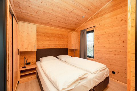 Chambre avec lit double, murs en bois, fenêtre à la Terrace Lodge avec sauna et jacuzzi, Pays-Bas.