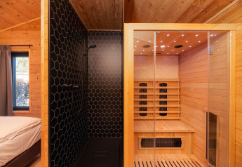 Lodge moderno con camera da letto, doccia nera e sauna in legno al Holiday Resort 't Schuttenbelt, Paesi Bassi.