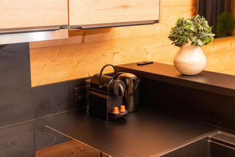 Moderne zwarte keuken met koffiemachine, waterkoker en plant in Terrace Lodge bij 't Schuttenbelt.