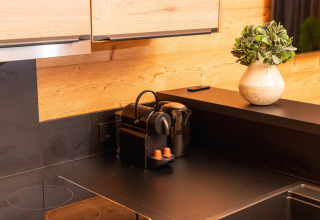 Cocina moderna negra con cafetera, hervidor y planta en Terrace Lodge, Holiday Resort 't Schuttenbelt, Países Bajos.