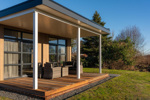 Moderne lodge met houten terras en zitgedeelte buiten bij Holiday Resort 't Schuttenbelt in Nederland.