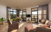 Lichte woonkamer met grote ramen en moderne inrichting in Vogellodge, vakantiepark 't Schuttenbelt, Nederland.