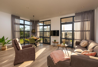 Modernes Wohnzimmer mit großen Fenstern und natürlichem Licht in der Vogellodge im Holiday Resort 't Schuttenbelt.