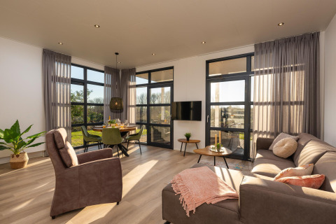 Modernes Wohnzimmer mit großen Fenstern und natürlichem Licht in der Vogellodge im Holiday Resort 't Schuttenbelt.