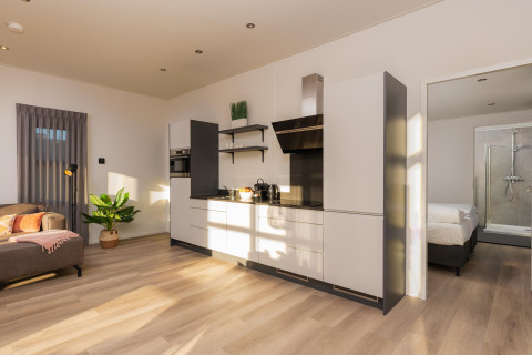Cucina moderna e soggiorno luminosi nella Vogellodge con vasca idromassaggio al Holiday Resort 't Schuttenbelt, Olanda.