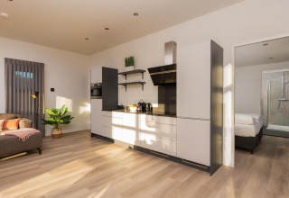 Cucina moderna e soggiorno luminosi nella Vogellodge con vasca idromassaggio al Holiday Resort 't Schuttenbelt, Olanda.