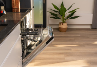 Open dishwasher in a modern kitchen at Vogellodge + hot tub in Holiday Resort 't Schuttenbelt, Netherlands.