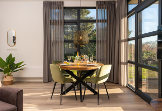 Essbereich in einer modernen Lodge mit großen Fenstern und Tageslicht im Holiday Resort 't Schuttenbelt, Niederlande.