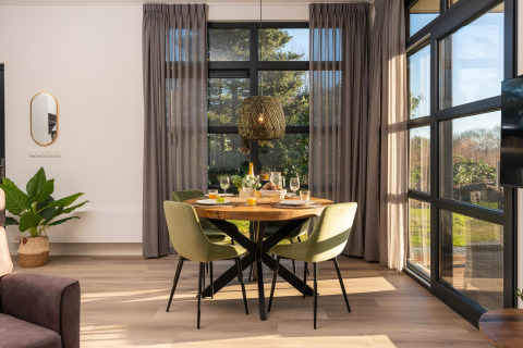 Zona pranzo in un moderno lodge con ampie finestre e luce naturale all’Holiday Resort 't Schuttenbelt, Paesi Bassi.