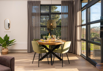 Spiseplads i moderne lodge med store vinduer og naturligt lys ved Holiday Resort 't Schuttenbelt i Holland.