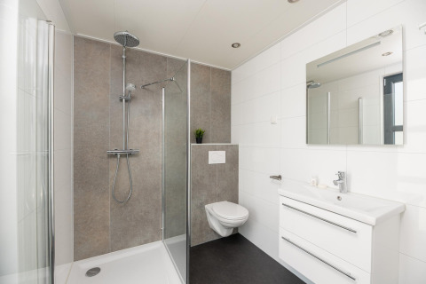 Bagno moderno alla Vogellodge con doccia, WC sospeso e lavabo presso il resort 't Schuttenbelt in Olanda.