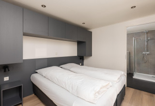 Dormitorio moderno con dos camas individuales y baño privado en Vogellodge + jacuzzi en los Países Bajos.