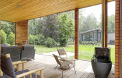 Überdachte Terrasse mit gemütlichen Sitzmöbeln und Gartenblick im Woody Lodge Florian, Niederlande.