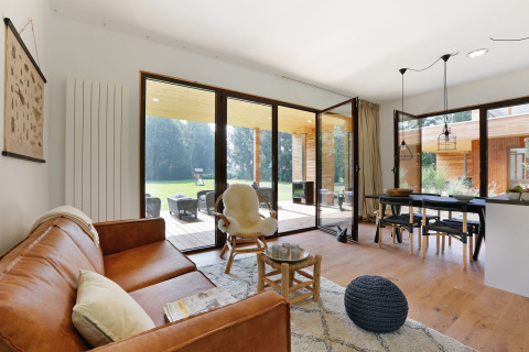 Moderne stue i Woody Lodge Florian på Holiday Resort 't Schuttenbelt med store glasdøre og udsigt til haven.