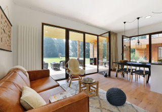 Modern living room at Woody Lodge Florian, Holiday Resort 't Schuttenbelt, Netherlands, with glass doors to patio.