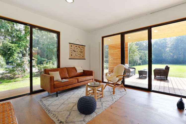 Helles Wohnzimmer in Woody Lodge Florian mit großen Fenstern und Blick auf Garten und Terrasse.