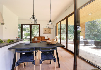 Moderne living van Woody Lodge Florian, grote ramen, eettafel en uitzicht op de natuur in Nederland.