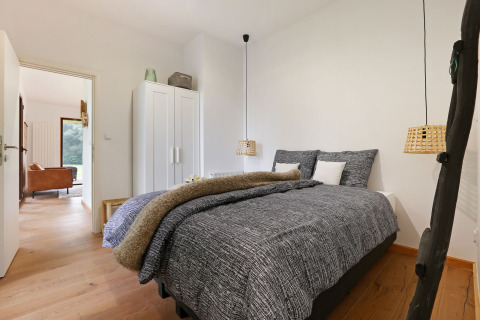 Moderne slaapkamer in Woody Lodge Florian met comfortabel tweepersoonsbed, kast en houten vloer.