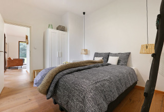 Dormitorio moderno en Woody Lodge Florian con cama doble, armario y decoración acogedora y natural.