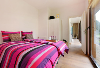 Dormitorio moderno en Woody Lodge Florian, Holiday Resort 't Schuttenbelt, Países Bajos, con ropa de cama colorida.