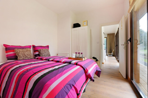 Moderne slaapkamer in Woody Lodge Florian op Holiday Resort 't Schuttenbelt, Nederland, met kleurrig beddengoed.