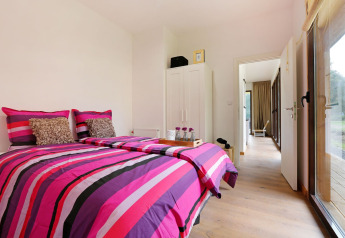 Moderne slaapkamer in Woody Lodge Florian op Holiday Resort 't Schuttenbelt, Nederland, met kleurrig beddengoed.