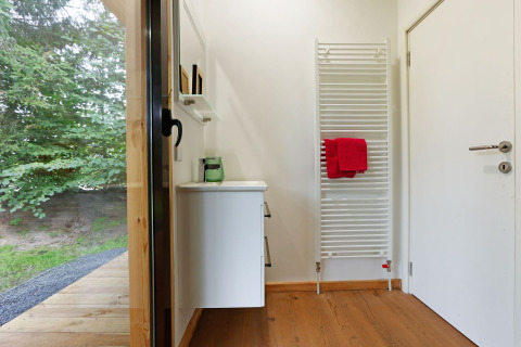 Entrance area at Woody Lodge Florian with wooden floor, heated towel rack and garden view outside.