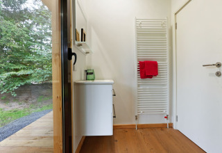 Entree bij Woody Lodge Florian met houten vloer, verwarmd handdoekenrek en uitzicht op de tuin.