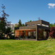 Tiny house moderne Woody Lodge Valerie au Holiday Resort 't Schuttenbelt, Pays-Bas, entourée de verdure.