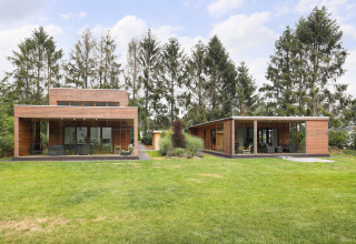 Two modern tiny wooden houses with large glass windows at Woody Lodge Valerie holiday resort in the Netherlands.