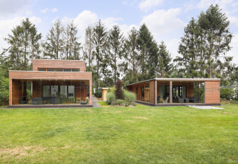 To moderne træhytter med store glasvinduer på en græsplæne ved Woody Lodge Valerie i Holland.