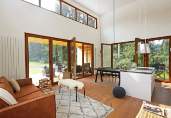 Lichte, moderne woonkamer met grote ramen in Woody Lodge Valerie op Holiday Resort 't Schuttenbelt in Nederland.