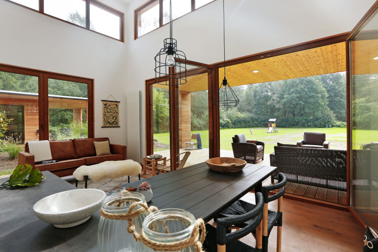 Sala luminosa en Woody Lodge Valerie con grandes ventanales y vista al jardín en Holiday Resort 't Schuttenbelt.