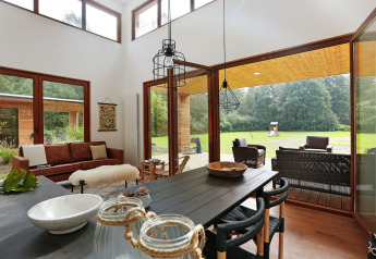 Sala luminosa en Woody Lodge Valerie con grandes ventanales y vista al jardín en Holiday Resort 't Schuttenbelt.